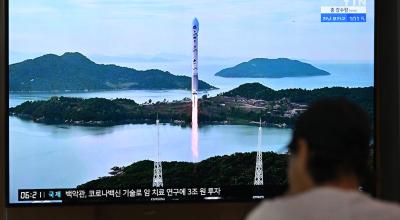 Un hombre mira una pantalla de televisión que muestra una transmisión de noticias con imágenes de archivo del lanzamiento de un cohete portador de un satélite norcoreano, en una estación de tren en Seúl el 24 de agosto de 2023.