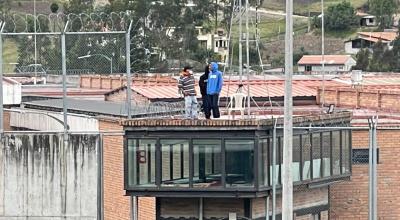 Dos privados de libertad en el techo de la cárcel de Turi, en Cuenca, durante los desmanes de este 1 de noviembre de 2023.