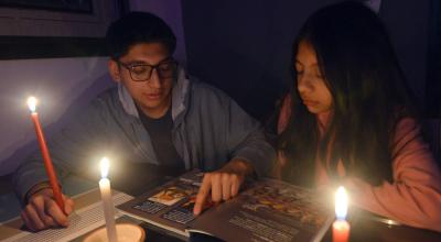 Renata y Daniel Barros estudiando con velas por el corte de energía eléctrica en Cuenca, el 27 de octubre de 2023. 