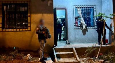 Dos policías en los exteriores de una vivienda allanada, durante la captura de 12 sujetos en Guayaquil, el 30 de noviembre de 2023.