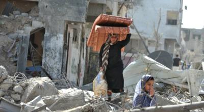 Una mujer y su hija rescatan sus últimas pertenencias de un barrio bombardeado en Gaza.