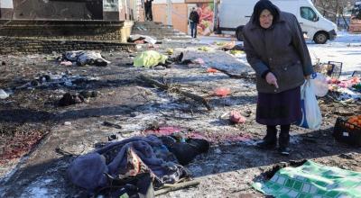 Una mujer se encuentra entre los cuerpos cubiertos de las víctimas que murieron en el bombardeo del mercado de alimentos en Donetsk, al este de Ucrania, el 21 de enero de 2024.