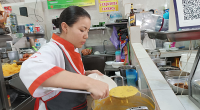 Una trabajadora de un local de comida en el mercado Santa Clara, en Quito, sirve un plato de Fanesca, 20 de marzo de 2024. 