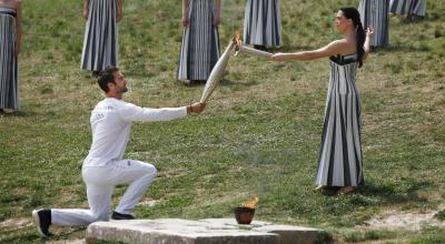 La actriz griega Mary Mina, en el papel de la Alta Sacerdotisa, pasa la llama olímpica al primer campeón olímpico griego de remo Stefanos Ntouskos, durante la Ceremonia de la Llama Olímpica de los Juegos Olímpicos de París 2024, el 16 de abril de 2024.