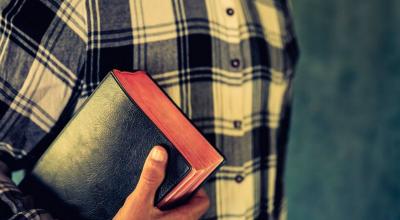 Imagen referencial de una persona con un libro religioso.