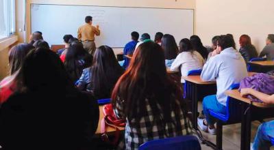 Estudiantes universitarios reciben clases presenciales en una aula.