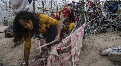 Migrantes de Venezuela se arrastran a través de un agujero en el alambre de púas para cruzar a Eagle Pass, Texas, el 25 de septiembre de 2023.