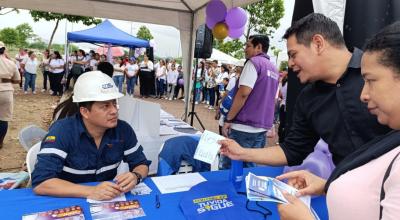 Personal de CNEL EP junto a dos ciudadanos en una feria de la empresa, realizada en Guayaquil, el 18 de mayo de 2024.