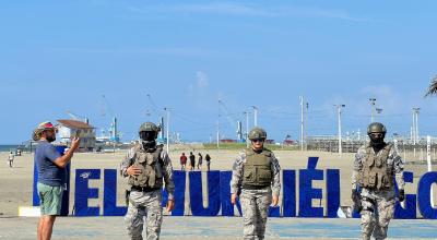 Un turista toma una fotografía a militares que vigilan la playa el Murciélago, en Manta, el 30 de marzo de 2024.