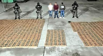 Policías posan junto a dos detenidos y un millar de paquetes de cocaína decomisados en Daule, el 24 de mayo de 2024.