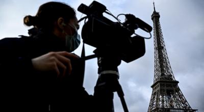 Un periodista filma frente a la Torre Eiffel, decorada con los anillos olímpicos de los próximos Juegos Olímpicos de París, el 17 de junio de 2024.