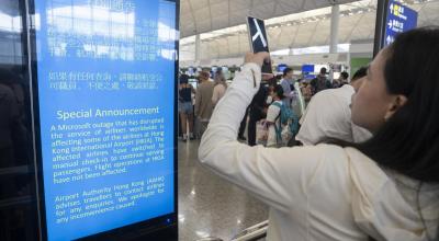 Una mujer toma fotografías a un anuncio sobre el fallo de Microsoft en un aeropuerto de Hong Kong, el 19 de julio de 2024.