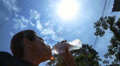 Una mujer se hidrata ante el intenso sol en Ecuador.