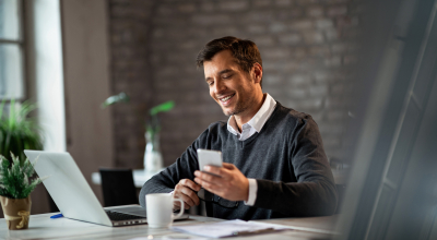 Empresario feliz trabajando con una computadora y un smartphone.