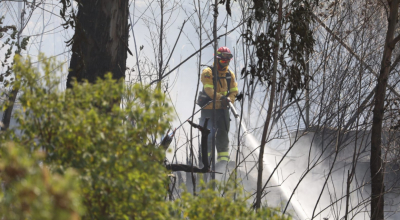 Un bombero realiza labores de enfriamiento de un incendio forestal en el sector La Cima de La Libertad, en Quito, este 26 de agosto de 2024.