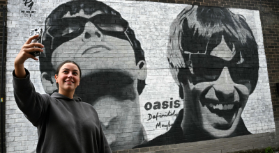 Una fan se toma una 'selfie' frente a un mural de los hermanos Liam and Noel Gallagher, de la banda Oasis, en Manchester, Inglaterra.